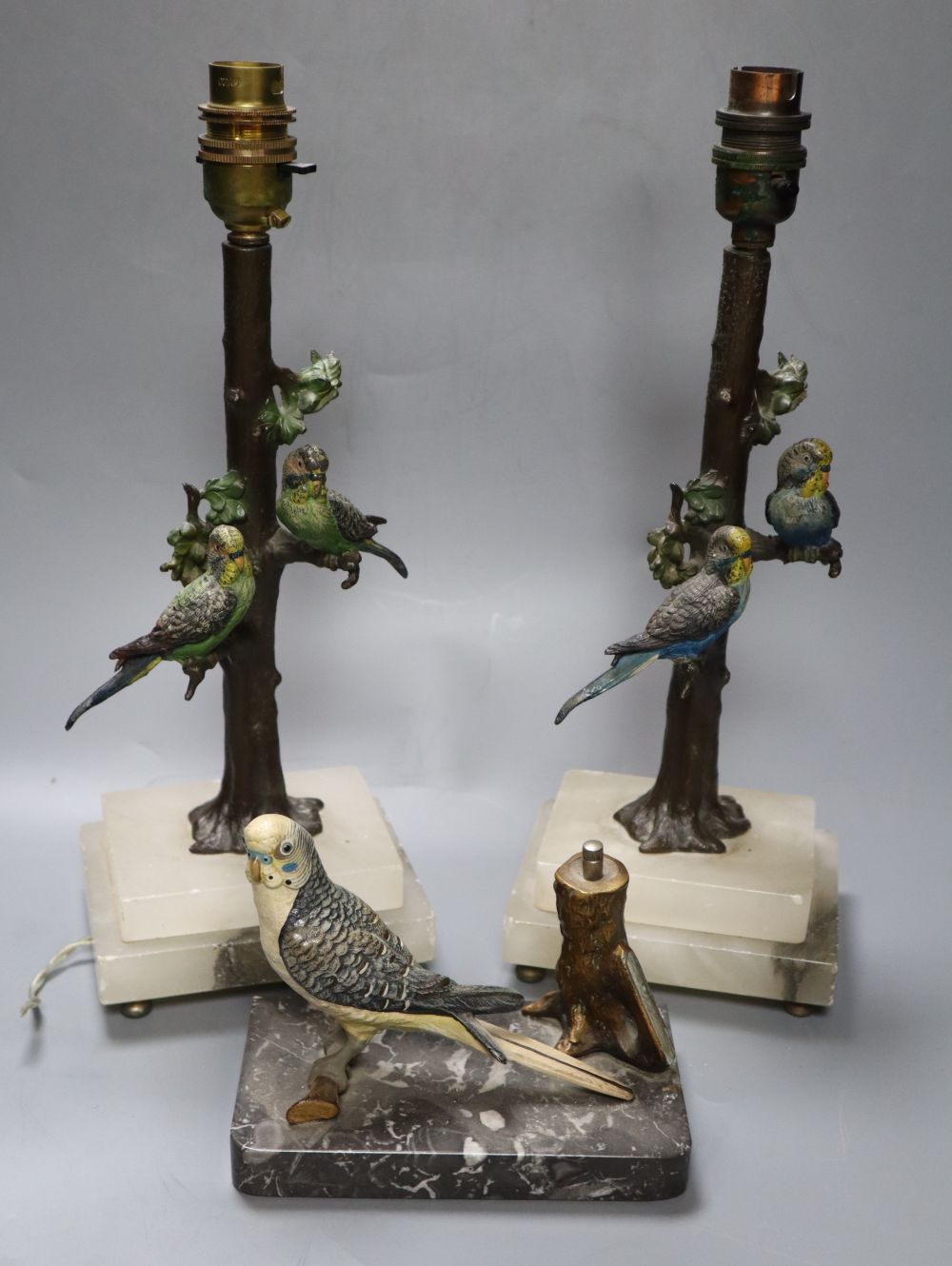 A pair of cold painted metal budgerigar lamps, height 28cm excl. light fitting and a cold painted metal budgerigar table lighter, width